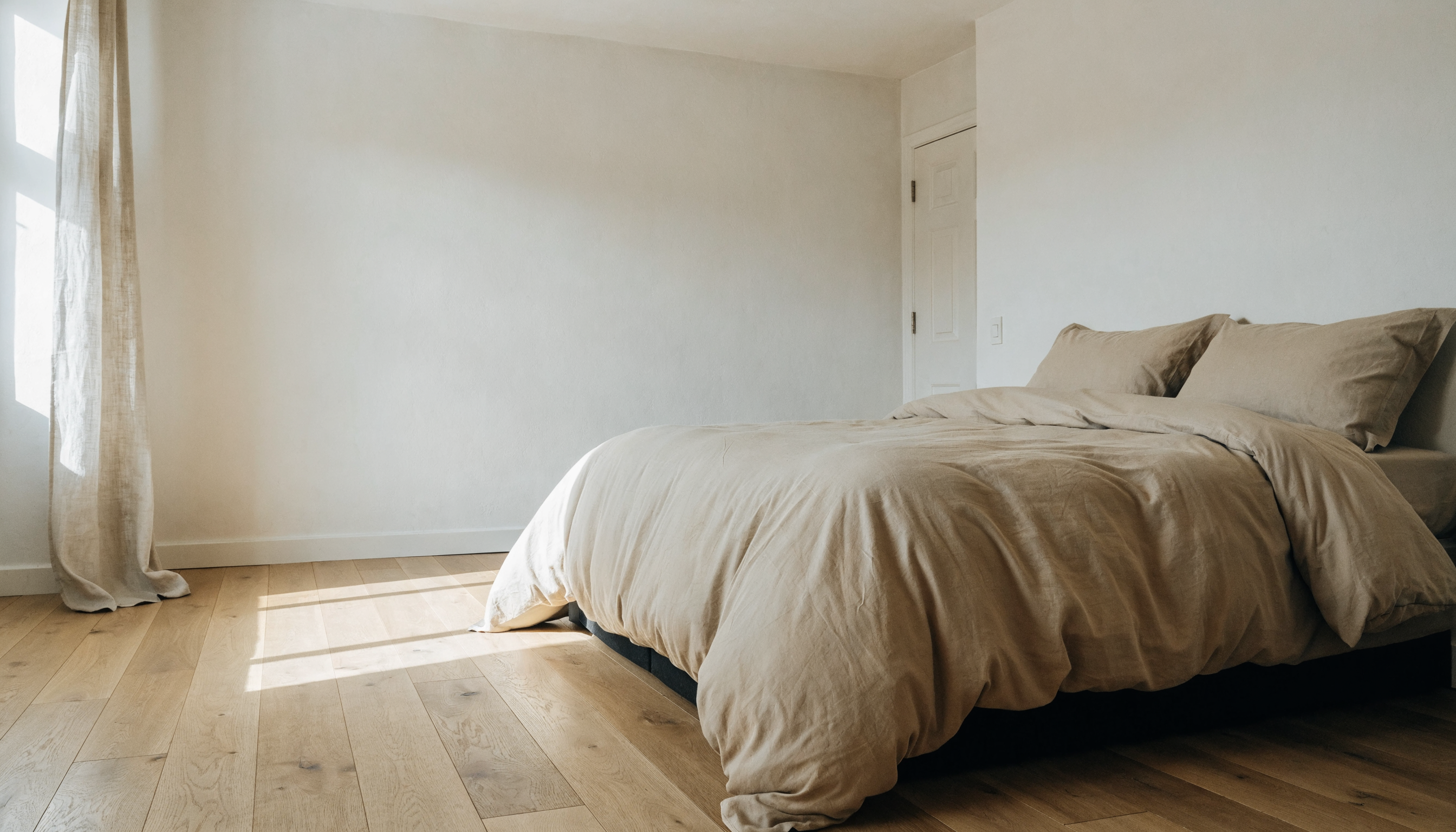 Lit deux places habillé d'une parure de lit en coton beige dans une chambre claire