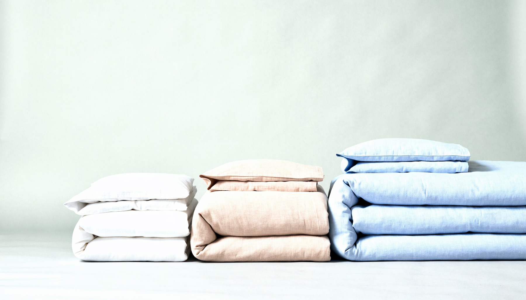 Trois parures de lit pliées avec leurs taies, de tailles croissantes